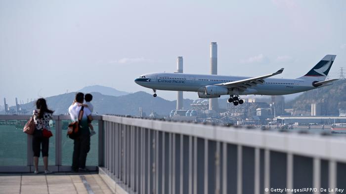 People watch as a Cathay Pacific passenger plane prepares to land at Hong Kong's international airport